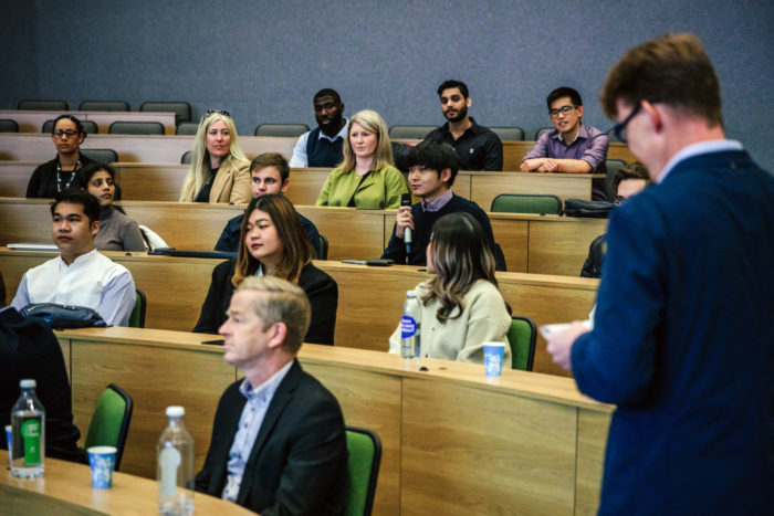 A crowd shot with a student holding the microphone and asking a question