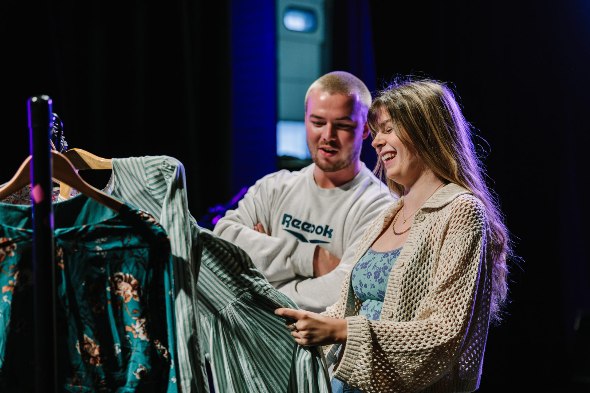Harry and Bethan smile and look at costumes in PCI Theatre