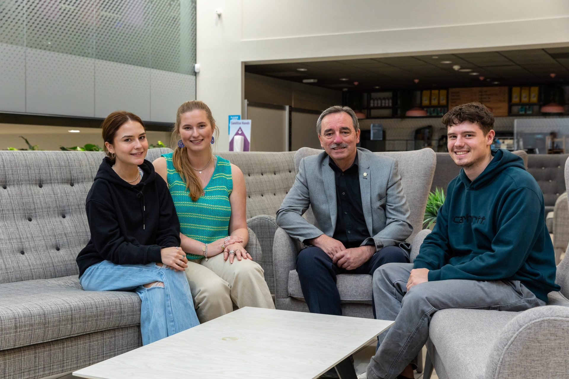 Image of enterprise students sat on sofa, smiling, with Stephen Curry